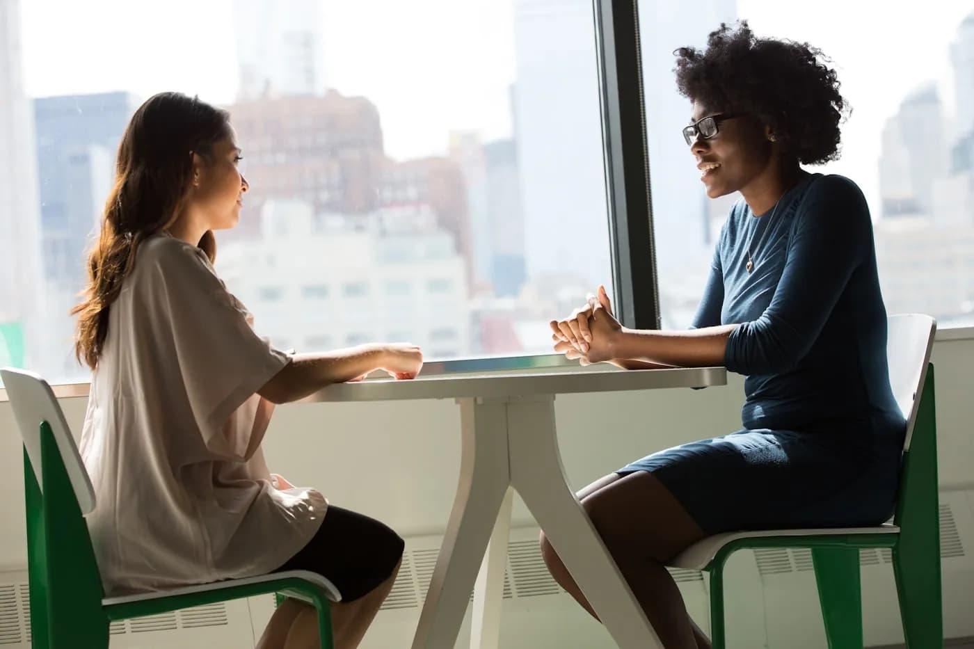 Two professionals in a private consultation beside a window with a city view